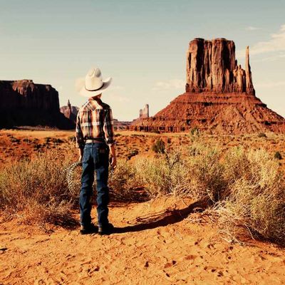 Enfant de dos en tenue de cow boy devant le site de Momunent valley